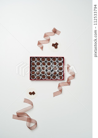 There is a box of individually packaged chocolate and a ribbon around it 112533794