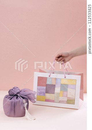 hold a traditional patterned shopping bag next to a gift cloth 112533825