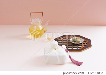 There is a plate of rice cake and a wooden fork on the traditional gate, and there are kettles, teacups, and gift cloths around it 112533834