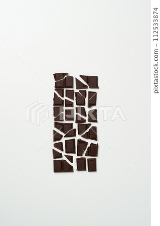 a piece of dark chocolate divided into dozens of pieces 112533874