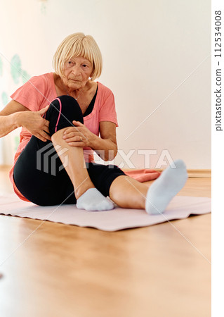 In a sunlit space, a senior woman gracefully practices rejuvenating yoga, focusing on neck, back, and leg stretches, embodying serenity and well-being In a sunlit space, a senior woman gracefully practices rejuvenating yoga, focusing on neck, back, and leg stretches, embodying serenity and well-being 112534008