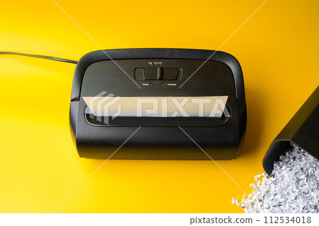 Office paper shredder on yellow studio background 112534018