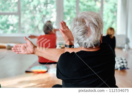 In a sunlit space, a senior woman gracefully practices rejuvenating yoga, focusing on neck, back, and leg stretches, embodying serenity and well-being In a sunlit space, a senior woman gracefully practices rejuvenating yoga, focusing on neck, back, and leg stretches, embodying serenity and well-being 112534075