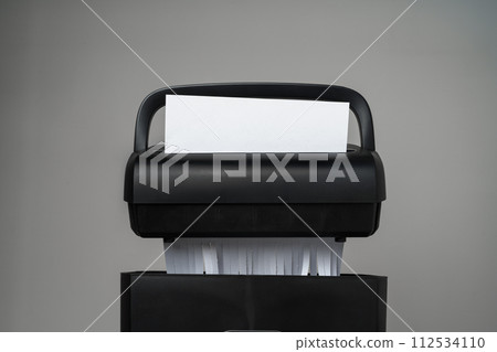 Black paper shredder cutting paper on gray background 112534110