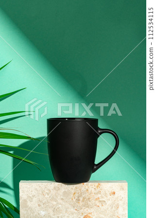 Porcelain mug and palm leaf against mint background 112534115