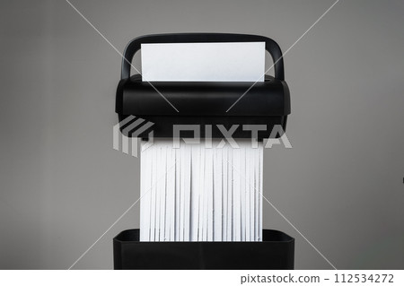 Black paper shredder cutting paper on gray background 112534272