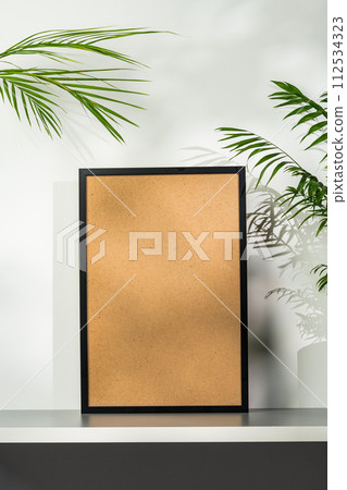 Black wooden photo frame and plant on gray background 112534323