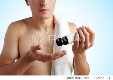 Young handsome man applies nourishing facial cream on white background Young handsome man applies nourishing facial cream on white background 112534921