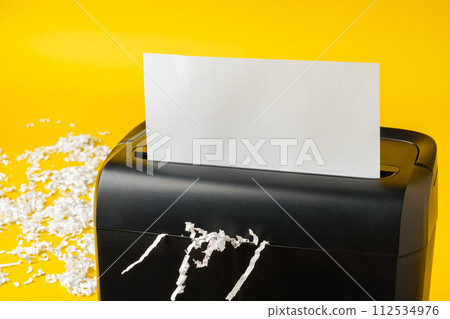 Office paper shredder on yellow studio background 112534976
