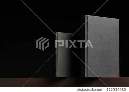 Black hardcover book or notepad mock up on black background Black hardcover book or notepad mock up on black background 112534980