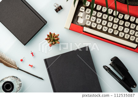Hardcover book and vintage typewriter on white desk 112535087