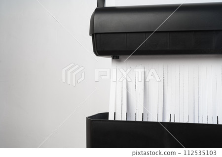 Black paper shredder cutting paper on gray background 112535103