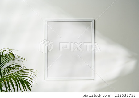 White wooden photo frame with plant leaves on white background White wooden photo frame with plant leaves on white background 112535735
