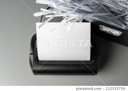 Black paper shredder cutting paper on gray background 112535739