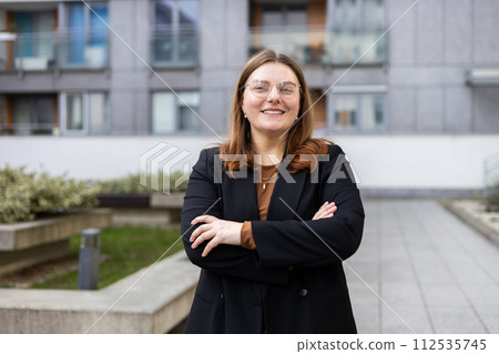 Caucasian 30s businesswoman standing in front of a building. Successful confident professional manager leader entrepreneur corporate employee posing with arms crossed on street Caucasian 30s businesswoman standing in front of a building. Successful confident professional manager leader entrepreneur corporate employee posing with arms crossed on street 112535745