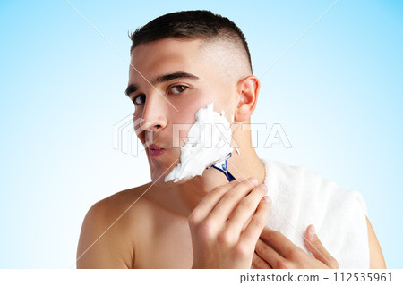 Young handsome man applying shaving foam against white background Young handsome man applying shaving foam against white background 112535961