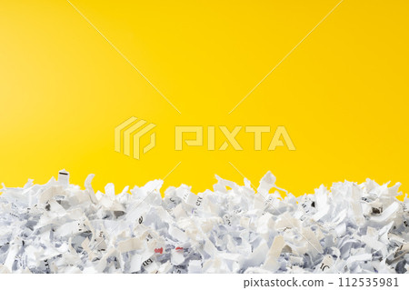Shredded white paper on light yellow background Shredded white paper on light yellow background 112535981