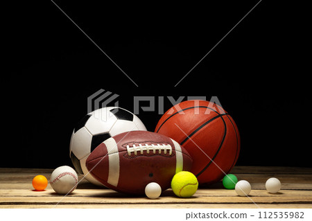 Set of various sport balls on wooden floor on black background 112535982