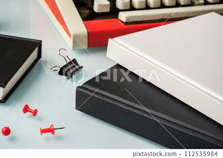 Hardcover book and vintage typewriter on white desk 112535984