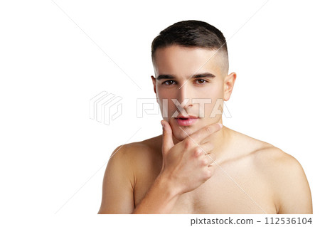 Young attractive brunet guy with perfect skin touching chin on white background 112536104