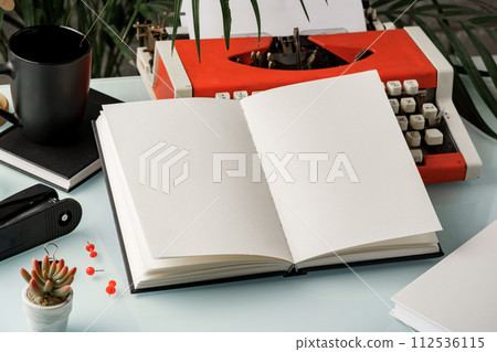Hardcover book and vintage typewriter on white desk Hardcover book and vintage typewriter on white desk 112536115