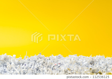 Shredded white paper on light yellow background 112536125