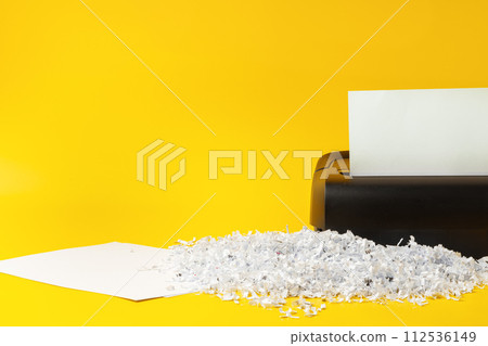 Office paper shredder on yellow studio background 112536149