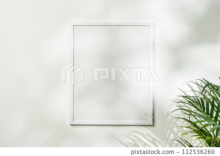 White wooden photo frame with plant leaves on white background 112536260