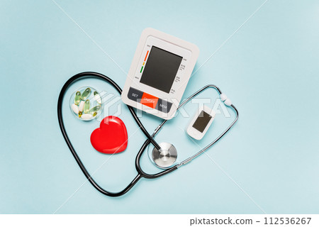 stethoscope, heart model, pills, and digital devices on Pale Blue Background symbolizing love and care in the medical field. stethoscope, heart model, pills, and digital devices on Pale Blue Background symbolizing love and care in the medical field. 112536267