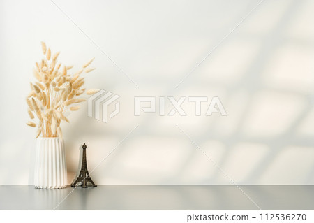 Ceramic vase with dried plant with shadows on the wall 112536270