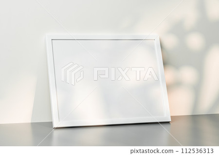 White wooden frame mock up on desk near white wall White wooden frame mock up on desk near white wall 112536313