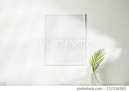 White wooden photo frame with plant leaves on white background 112536383