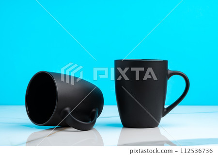 Two ceramic mugs on blue studio background 112536736