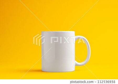 Ceramic mug on yellow studio background close up 112536938