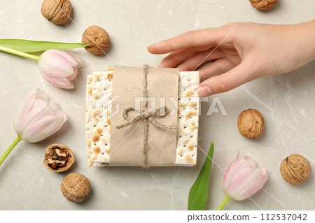 Matzo, hand, flowers and nuts on beige background, top view 112537042