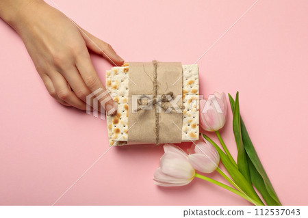 Matzo, hand and flowers on pink background, top view 112537043