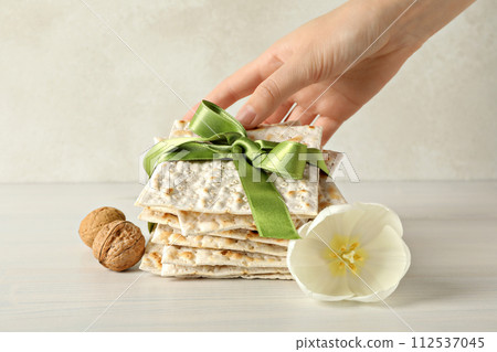 Matzo in hand, nuts and flower on beige background 112537045