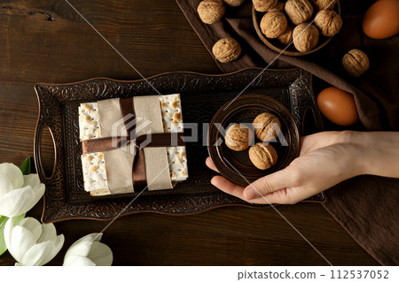 Matzo, nuts, female hand, eggs and flower on tray on wooden background, top view Matzo, nuts, female hand, eggs and flower on tray on wooden background, top view 112537052