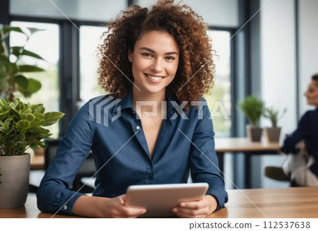 AI-generated content. A woman in a navy shirt sits working with a tablet in a bright office space, with a confident smile. 112537638