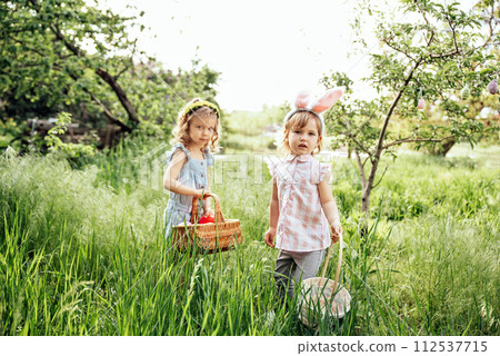 Easter egg hunt. Group Of Children Wearing Bunny Ears Running To Pick Up colorful Egg On Easter Egg Hunt In Garden. Easter tradition Easter egg hunt. Group Of Children Wearing Bunny Ears Running To Pick Up colorful Egg On Easter Egg Hunt In Garden. Easter tradition 112537715