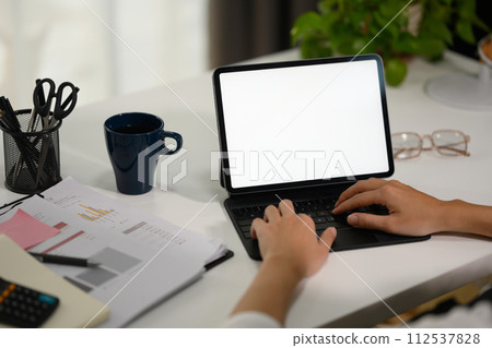 Unrecognizable businesswoman typing on keyboard, using digital tablet at office desk 112537828