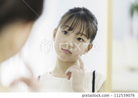 An elementary school girl worries when she looks in the mirror in the morning An elementary school girl worries when she looks in the mirror in the morning 112539076