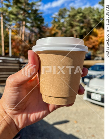 A person is holding a cup with a lid on it A person is holding a cup with a lid on it 112539732