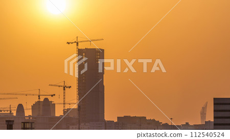 A tower in Doha timelapse, Qatar, under construction, silhouetted against the sunset. A tower in Doha timelapse, Qatar, under construction, silhouetted against the sunset. 112540524