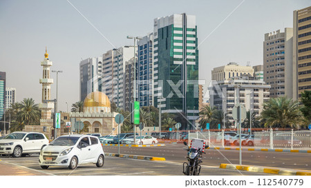 Corniche boulevard beach park along the coastline in Abu Dhabi timelapse with skyscrapers on background. 112540779