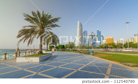Corniche boulevard beach park along the coastline in Abu Dhabi timelapse hyperlapse with skyscrapers on background. 112540780