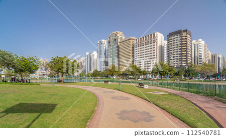 Corniche boulevard beach park along the coastline in Abu Dhabi timelapse hyperlapse with skyscrapers on background. 112540781
