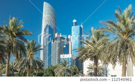 Corniche boulevard beach park along the coastline in Abu Dhabi timelapse with skyscrapers on background. 112540961