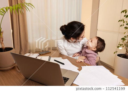 happy woman working and and playing with her baby daughter at home happy woman working and and playing with her baby daughter at home 112541199