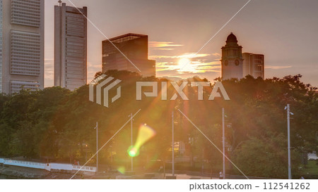 Sunset over Singapore skyscrapers skyline with white Anderson Bridge near esplanade park timelapse. 112541262